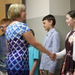 Graduates greet their classmates and teachers with a handshake
