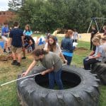 Middle school science classes help install tires in playground.