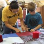 Kindergarten students and eighth graders worked in pairs to knot comforters.