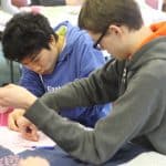 Luka Sakai, left, joined the EMS community from his home in Michigan. Here he and another student knot a comforter for Mennonite Central Committee.