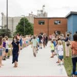 Grades K-4 line the sidewalk to cheer on 5th grade student graduates. Photo courtesy of Christy McKee