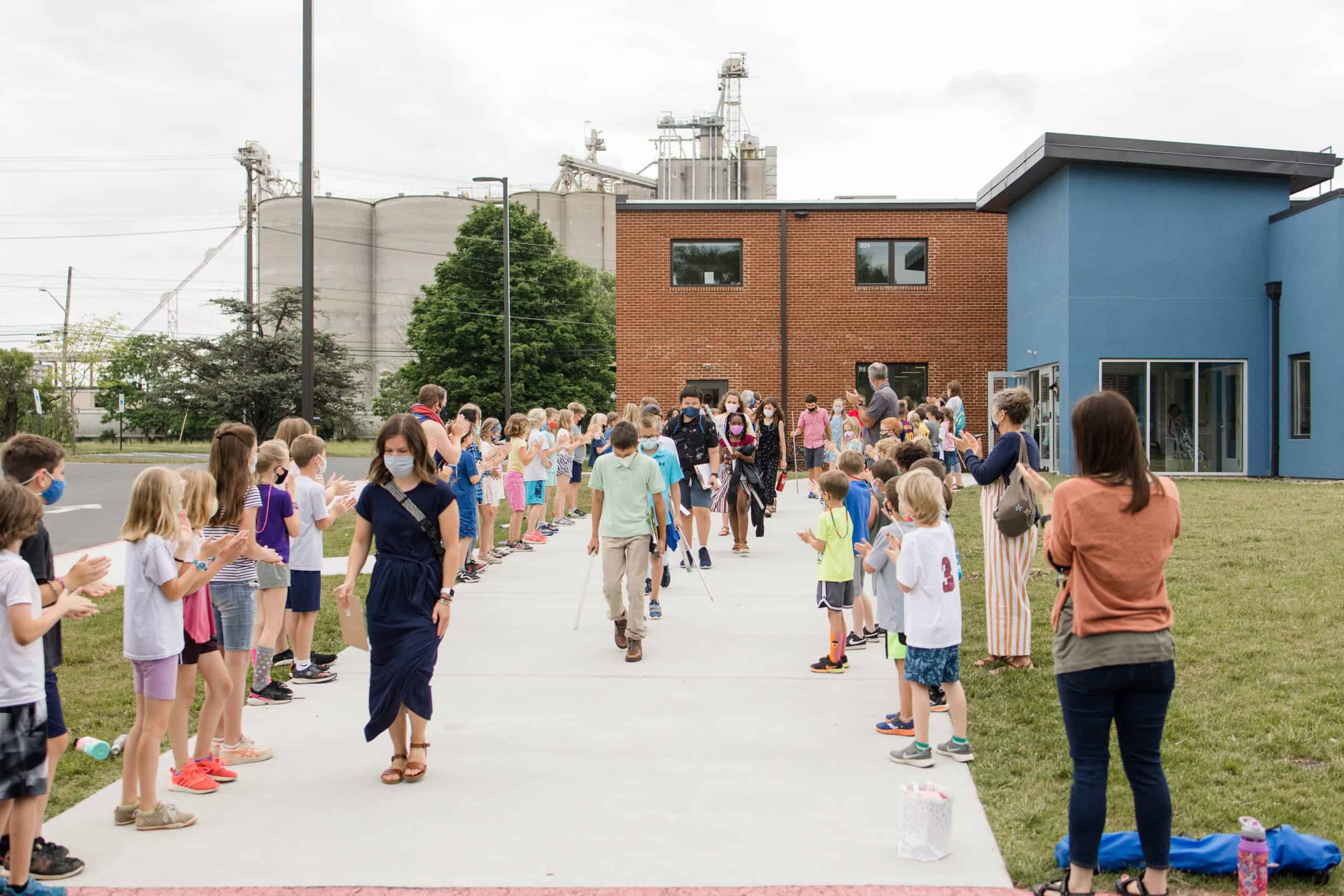 Grades K-4 line the sidewalk to cheer on 5th grade student graduates. Photo courtesy of Christy McKee