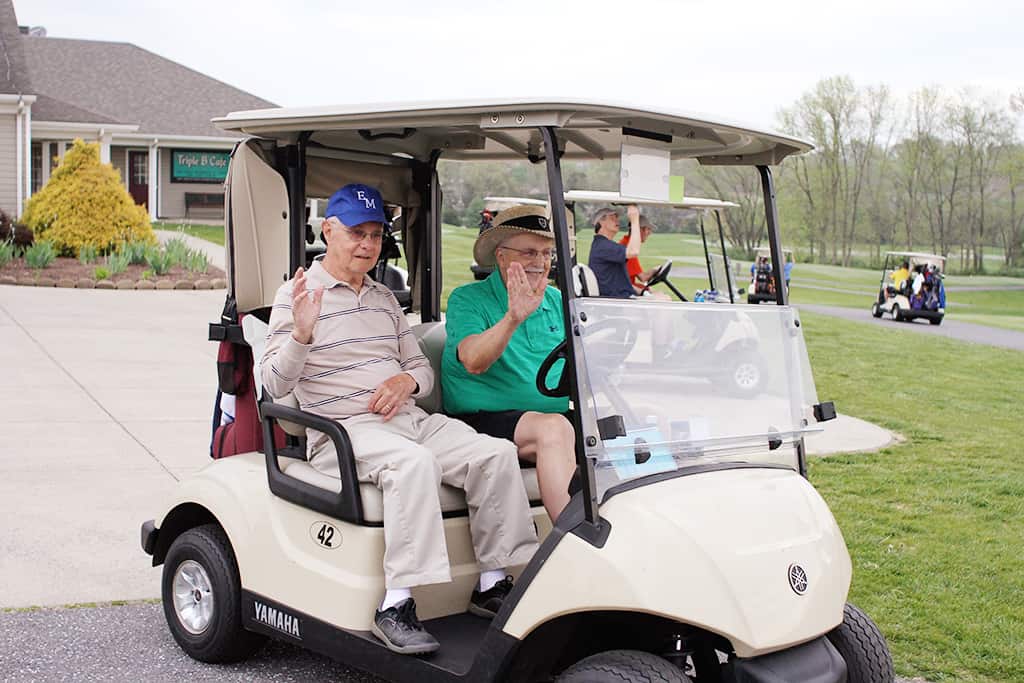 Men riding in a golf cart at the Fore the Flame 2018 golf fundraiser