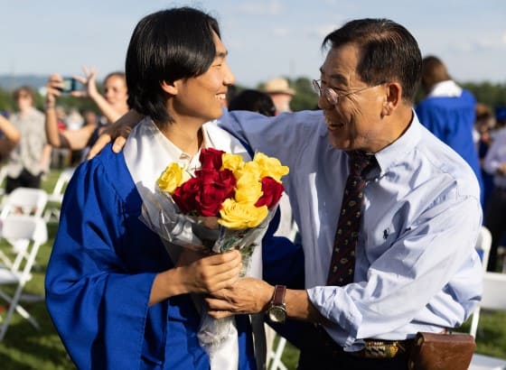 Father congratulates son at graduation with flowers