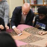 Benjamin Bixler and his Bible 9 students knot comforters for Mennonite Central Committee