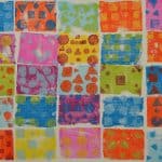 Title: The Colorful Ghosts
Size: 24”x18”
Media: acrylic paint
Description: 1st grade artists used printmaking to create a colorful quilt-like composition. Each student rolled paint onto a rectangular piece of foam and stamped the shape onto the wooden panel. After designing a printmaking block with foam shapes, they rolled paint onto it and stamped it directly over their solid block of color. Students repeated this process with a partner to create a second print. These student pairs practiced sharing their ideas for design and color choices. The last printed block was created by the entire class. As the final step in their creative process, the class brainstormed title ideas for their piece then voted for their favorite.

